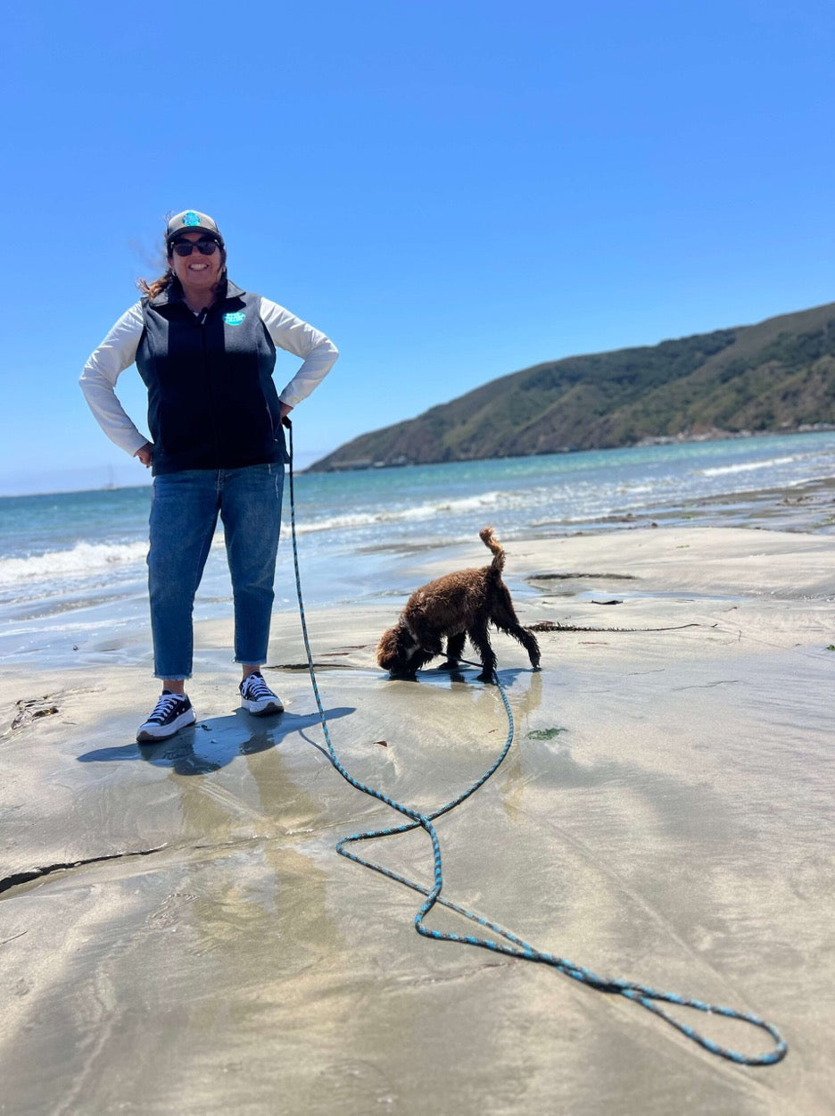 Woman and dog at beach with beach and lake long leash