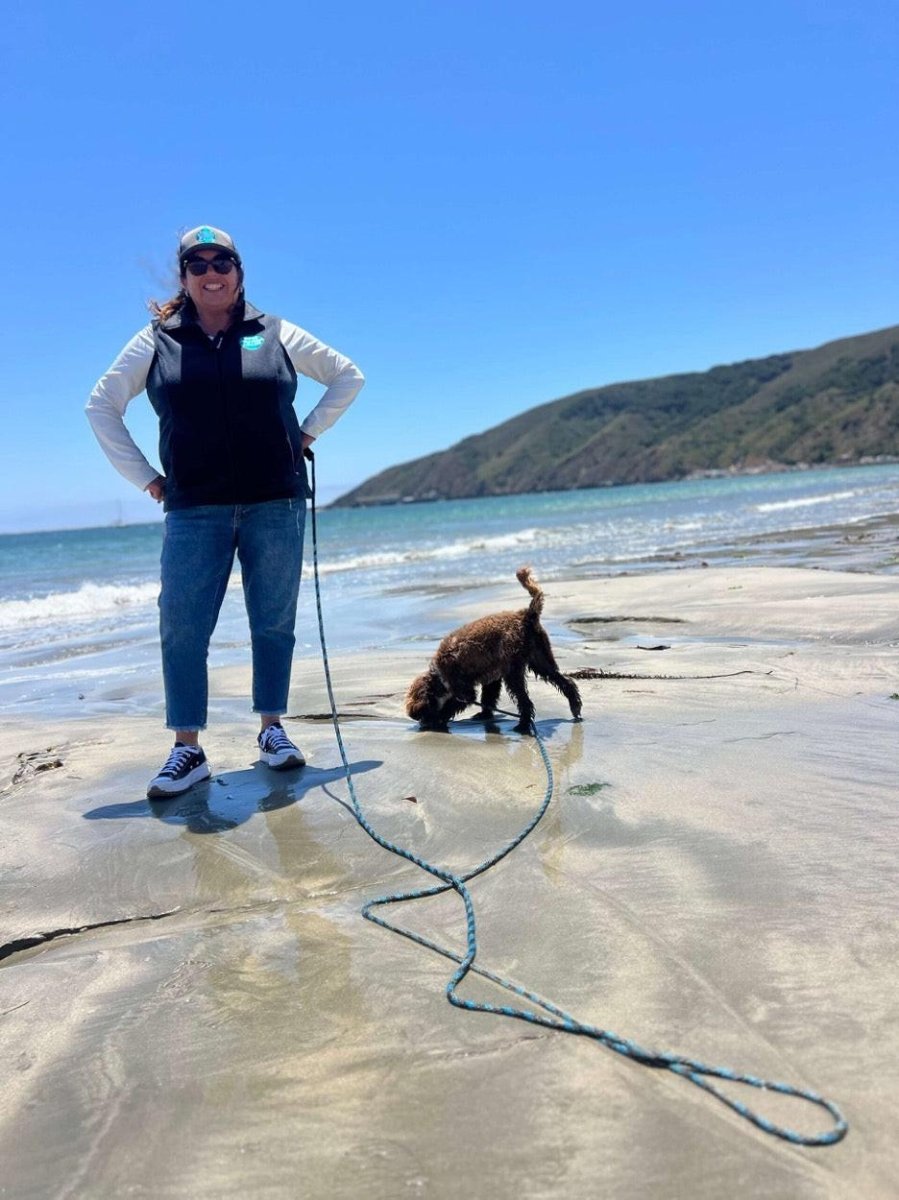 Woman and dog at beach with beach and lake long leash