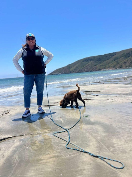 Woman and dog at beach with beach and lake long leash